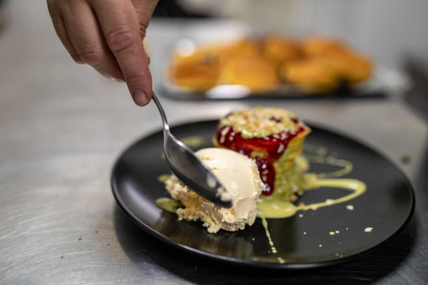 istock Chef puts vanilla ice cream on pancakes with pistachio cream and raspberry jam served at kitchen island 1406135852
