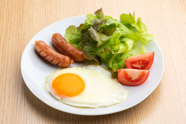 Wiener sausage, fried egg and salad on a plate.