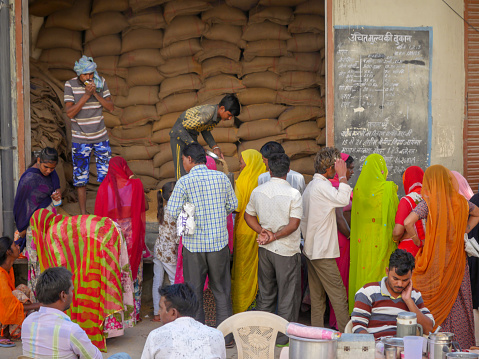 Pushkar, Rajasthan / India - November 5, 2019 : Public gather outside Indian government ration store. public distribution shop, also known as fair price shop (FPS), is a part of India's public system established by the Government of India which distributes rations at a subsidized price to the poor.