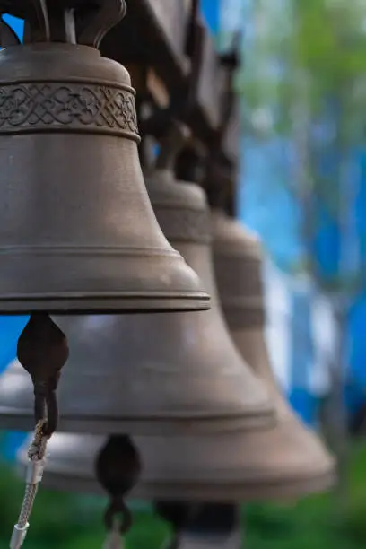 Photo of Russian church bells outdoors on blue blurred background. several Church bells, bell ringing.