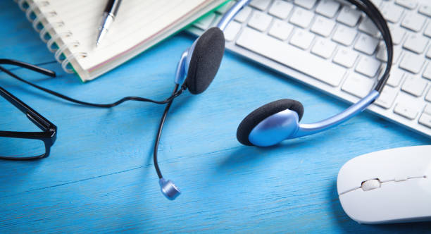 istock Customer service headset, computer keyboard and business objects on the blue background. 1406138160