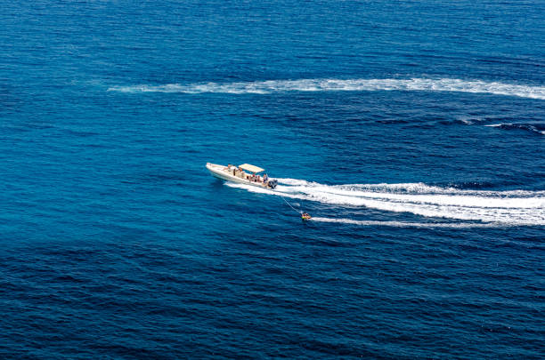 La Spezia, Italy - July 23, 2022: White motorized dinghy with three people on board (a man and two women), in motion on a sunny summer day in the Mediterranean sea, Gulf of La Spezia or Gulf of Poets, Liguria, Italy, southern Europe.