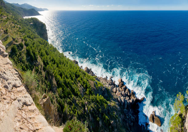 Views across the Mediterranean Sea to the horizon. Beneath wooded cliffs.
