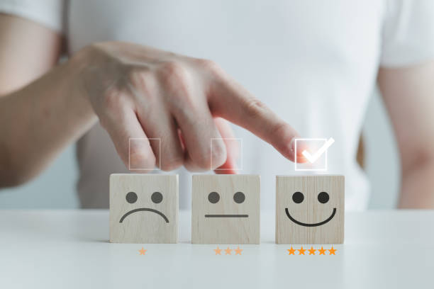 istock Customer service rating experience and feedback emotion and satisfaction survey with star and negative, neutral and positive facial expressions. hand choose 5 star happy smiley face icon on wood cube. 1406139157