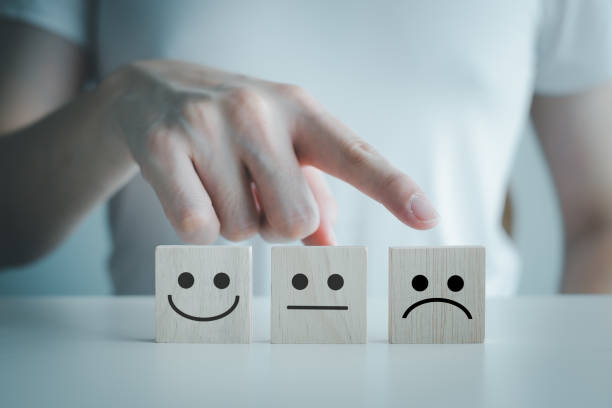 istock Customer service rating experience and feedback emotion and satisfaction survey and negative, neutral and positive facial expressions. hand choose sad face icon on wood cube. 1406139159