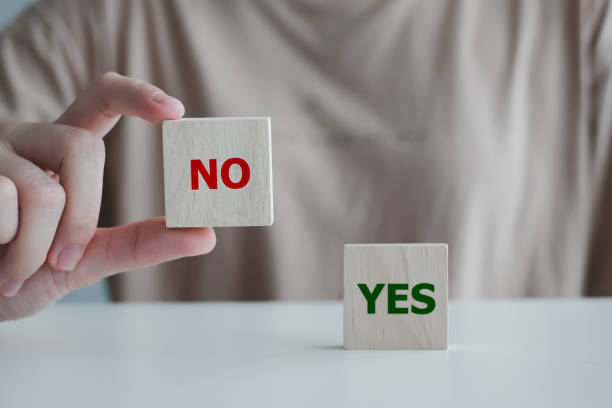 istock Think With Yes Or No Choice.Test question. Choice hesitate, opposition, opponent view. making decision. Woman hand showing No word on wood cube with Yes text didn't choose stand on table. 1406139171