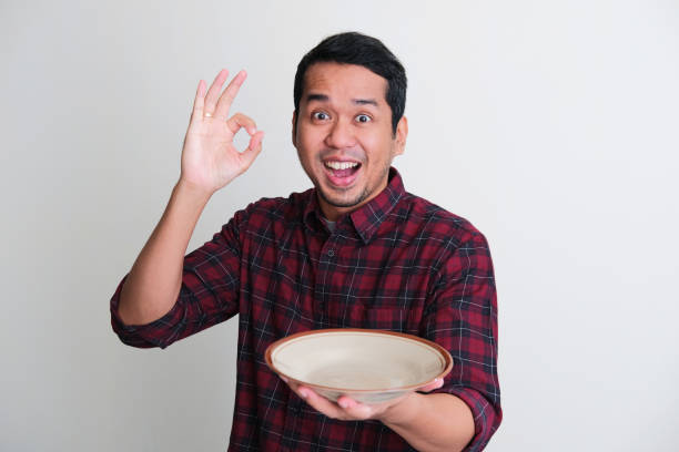 istock Adult Asian man give ok sign and showing enthusiastic expression while holding empty dinner plate 1406140791