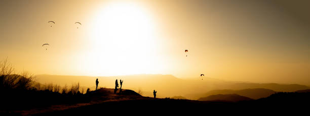 amazing panorama silhouette of paragliding in landscape with mountains at sunset and yellow sky - forest black forest sky night imagens e fotografias de stock