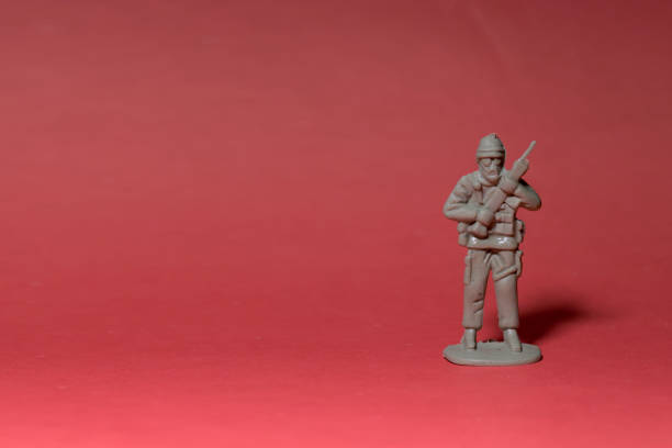 istock Miniature toy soldier with weapon in hand, reddish background 1406143872