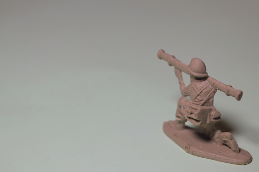 Miniature toy soldier with weapon in hand, white background