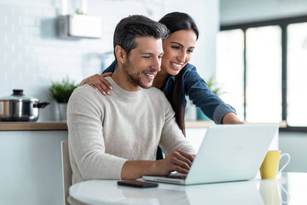 istock Beautiful lovely couple using their laptop while having breakfast in the kitchen at home. 1406145302