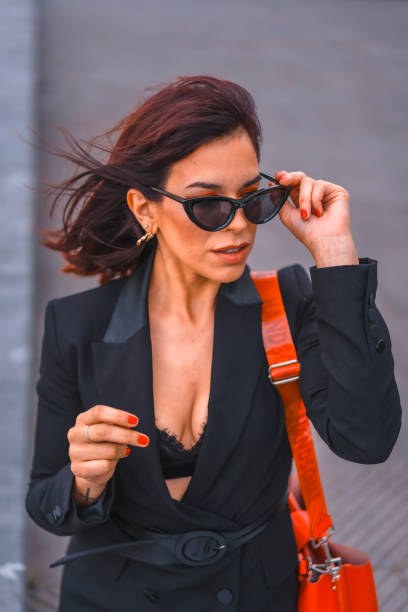 fashion pose. gorgeous brunette girl in the city with sunglasses looking at the camera - beach stone wall one person imagens e fotografias de stock