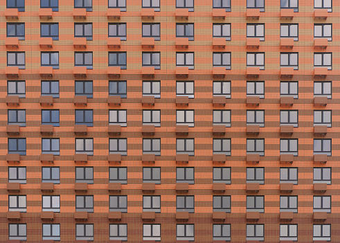 Facade of a new multi-apartment high-rise residential building with windows background. Architecture and design of a typical development of a new city district. Construction, developer, housing concept. High quality photo