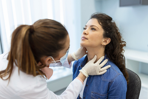 Endocrinólogo examinando la garganta de una mujer joven en la clínica. Mujeres con prueba de glándula tiroides. Endocrinología, hormonas y tratamiento. Inflamación del dolor de garganta photo