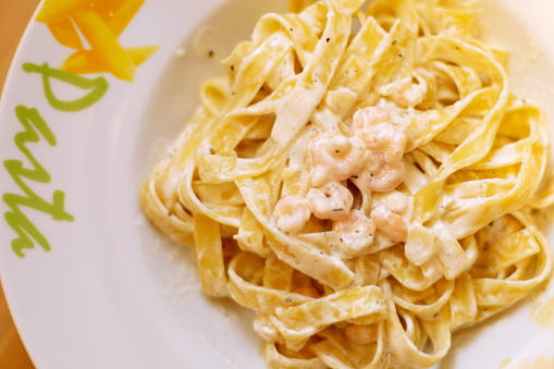 Tagliatelle pasta with shrimps with sauce in plate top view. Italian dish