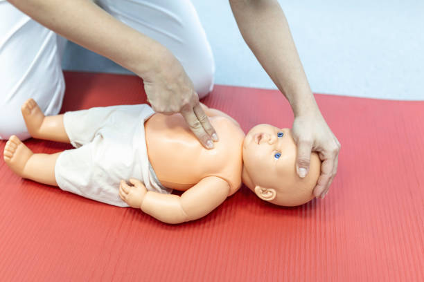 istock Woman performing CPR on baby training doll with one hand compression. First Aid Training - Cardiopulmonary resuscitation. First aid course on cpr dummy. 1406152262