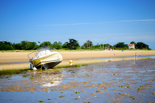 A motorboat laying on the beach at lowtide on a sunny summertime on the Isle of île de re in the Charente-Maritime in France