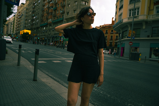 Young woman with blank black t-shirt is walking in the city