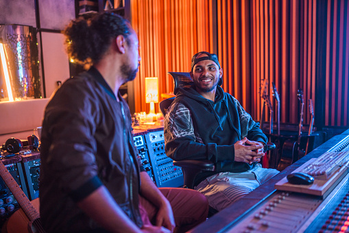 Two Male Musicians Operating With Sound Recording Studio Mixer