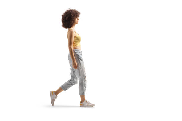 full length profile shot of a young caucasian woman with afro hairstyle walking - wandelen stockfoto's en -beelden