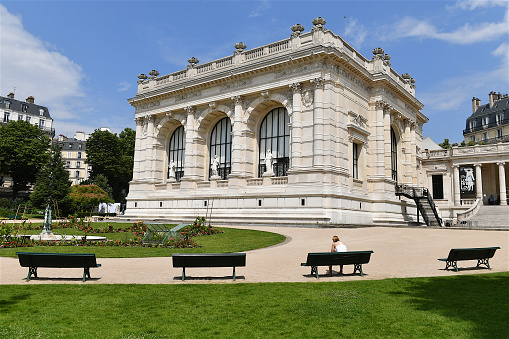 Paris, France-06 22 2022: One person on a bench in the garden of the Palais Galliera .The Palais Galliera, also formally known as the Musée de la Mode de la Ville de Paris (City of Paris Fashion Museum), and formerly known as Musée Galliera, is a museum of fashion and fashion history located in the 16th arrondissement of Paris, France.