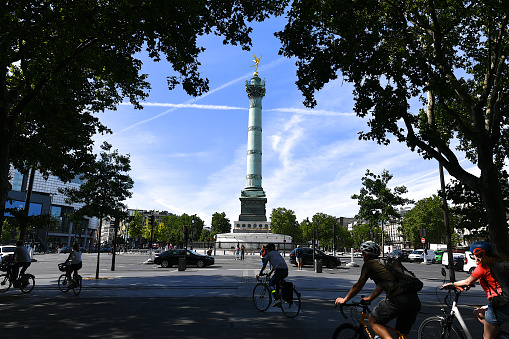 Paris, France-06 29 2022:People and cyclists passing next of the July Column which stands at the center of the Bastille square in Paris, France.The July Column (Colonne de Juillet) commemorates the events of the July Revolution (1830).