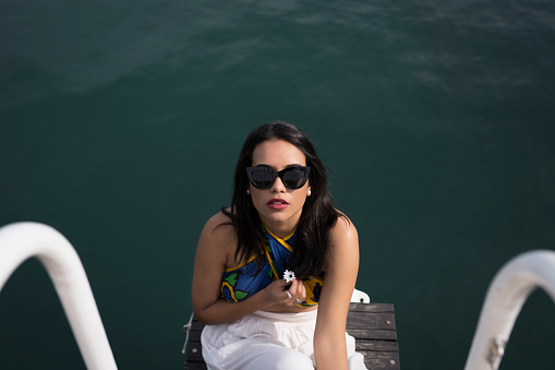 Attractive woman in sunglasses sitting on a bench and looking at the camera