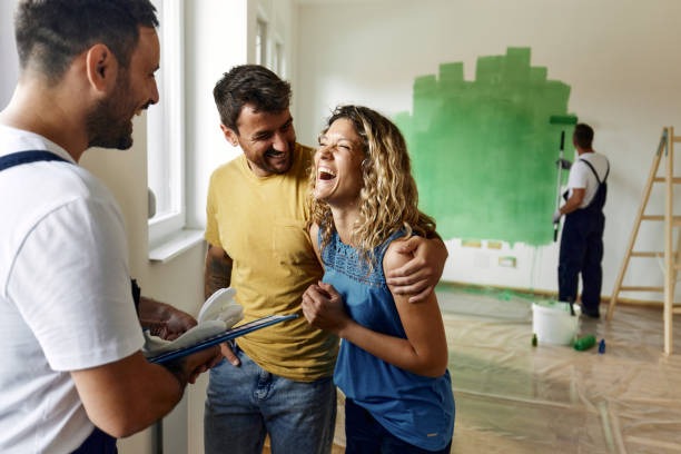 istock Cheerful couple talking to their house painter during home renovation process. 1406164362