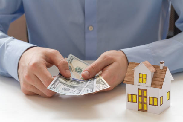 istock Hands counting dollar bills with house figurine 1406166772