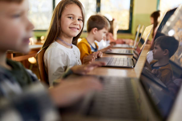 istock Happy schoolgirl using laptop on a class at elementary school. 1406167017