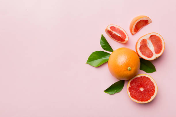 fresh Fruit grapefruit with Juicy grapefruit slices on colored background. Top view. Copy Space. creative summer concept. Half of citrus in minimal flat lay with copy space stock photo