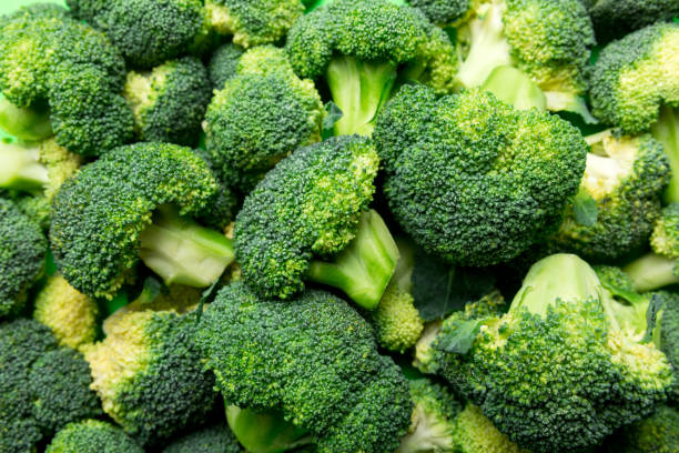 istock green fresh broccoli background close up on colored table. Vegetables for diet and healthy eating. Organic food 1406168343