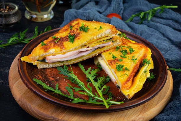 istock Roasted toast in scrambled eggs with ham, herbs and cheese cheddar. Delicious grilled breakfast sandwich 1406168609