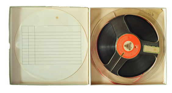 Vintage magnetic audio reel in cardboard box and blank paper inlay, free copy space