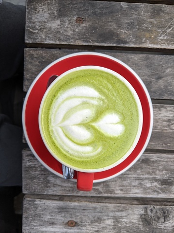 A cup of matcha latte on the wood table