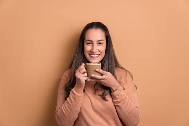 istock brazilian woman drinking a latte, in beige studio background. 1406176206