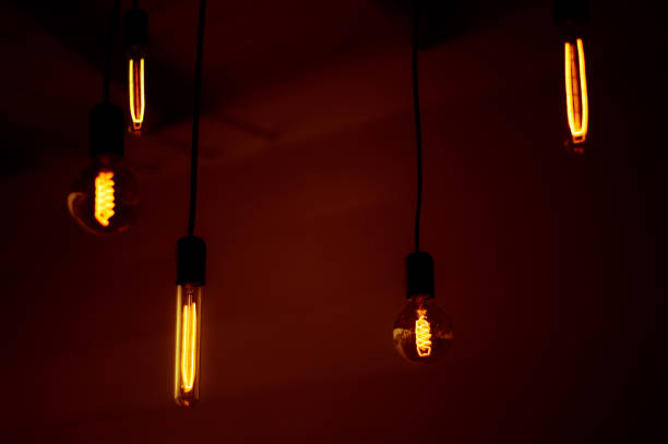 istock Group of tungsten light bulbs in the dark. 1406177648