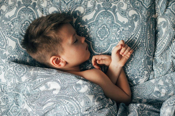 istock Adorable boy 6-7 years old sleeping in bed. Child having a good dreams. 1406177716