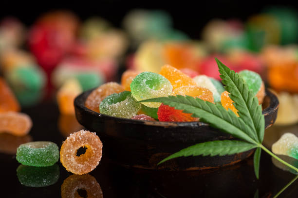 Colored candy gelatin in a black bowl with marijuana leaves stock photo