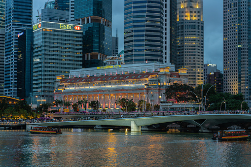 Singapore, Singapore - Feb 24, 2018: Blue hour view of The Fullerton Hotel with tourboats in the water