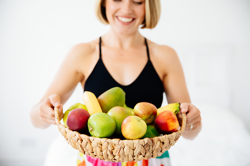 Woman holding crate filled with variety of fruits