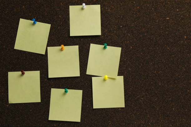 istock Beige paper notes pinned to cork board. Space for text 1406181460