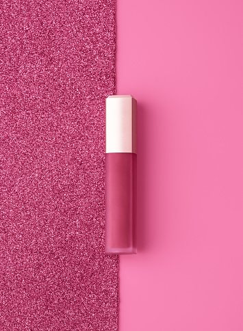 Composición plana con brillo de labios dorado rosa vivo sobre fondo rosa brillante y brillante. photo