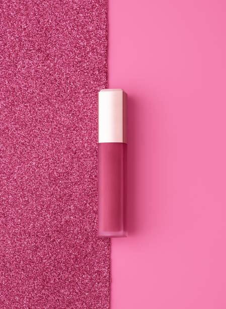 composición plana con brillo de labios dorado rosa vivo sobre fondo rosa brillante y brillante. - gloss de labios fotografías e imágenes de stock