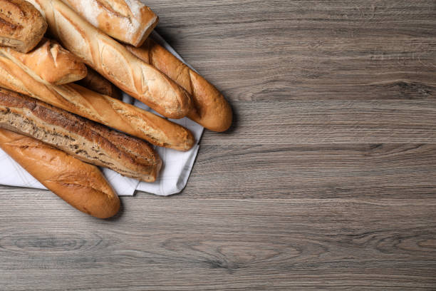istock Different tasty baguettes on wooden table, flat lay. Space for text 1406182099