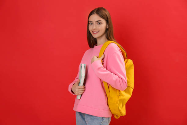 istock Teenage student with backpack and book on red background 1406182221