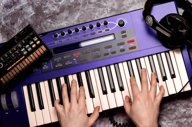Photo of Top view of synthesizer keyboard piano with male hands . Music maker equipment.