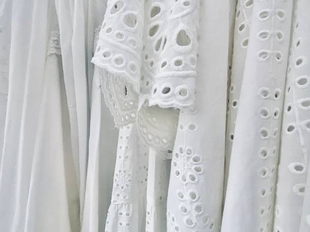 Horizontal close up of white cotton fabric summer dresses on hanging rack