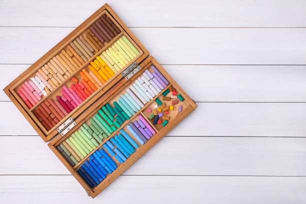 istock Set of soft pastels in box on white wooden table, top view with space for text. Drawing material 1406182944