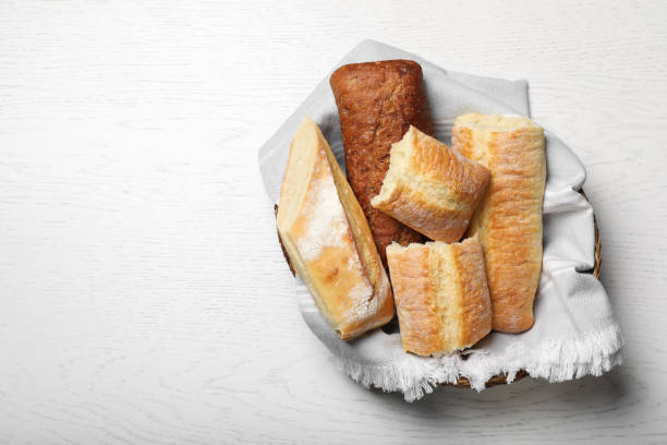 istock Different tasty baguettes in basket on white wooden table, top view. Space for text 1406183074